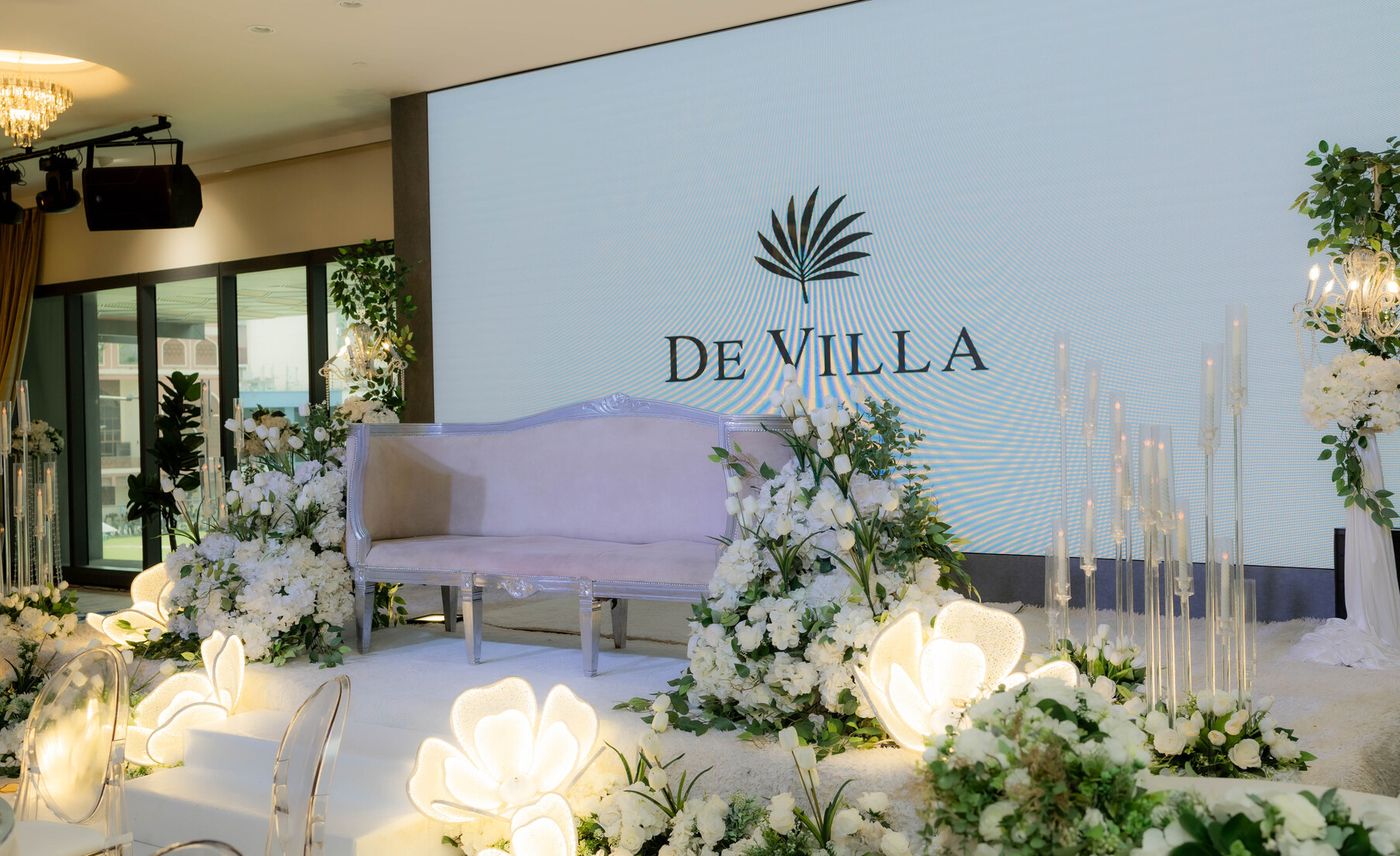 The De Villa stage with the logo on the LED screen and white florals